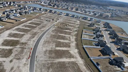 A view of an empty lot with houses in the background.